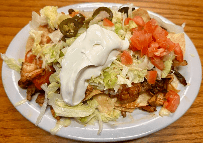 A loaded plate from Acapulco Mexican Grill topped with sour cream, tomatoes and jalapenos