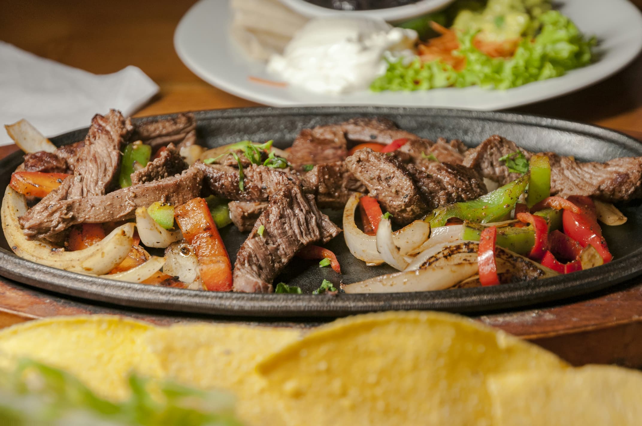 Sizzling steak fajitas with peppers and onions on a cast-iron skillet